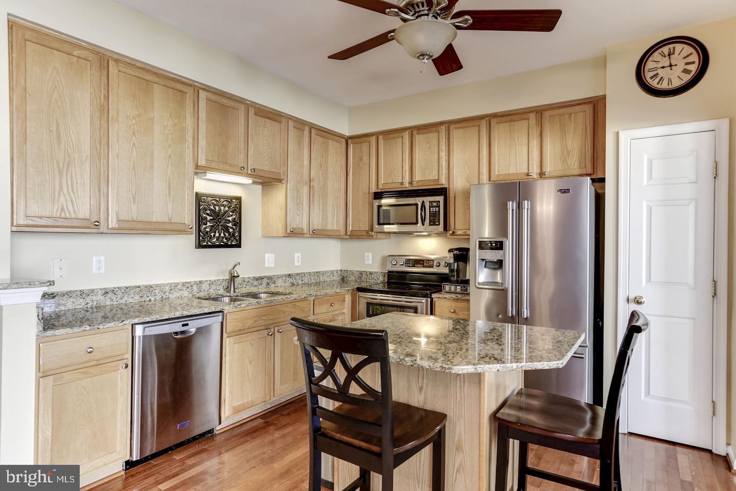 10106 Sir Reynard Lane Bristow, VA 20136 - Photo 9 of 28 a kitchen with stainless steel appliances granite countertop a stove a refrigerator a sink a stove with island cabinets and wooden floor