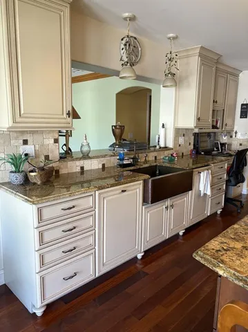 a kitchen with granite countertop a sink cabinets and wooden floor