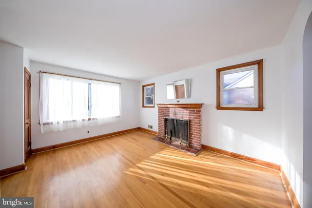 a view of empty room with wooden floor and fireplace