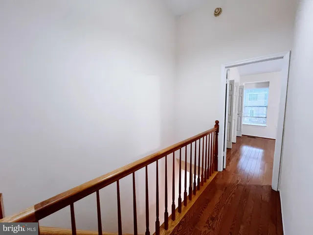 a view of an empty room with wooden floor and a ceiling fan