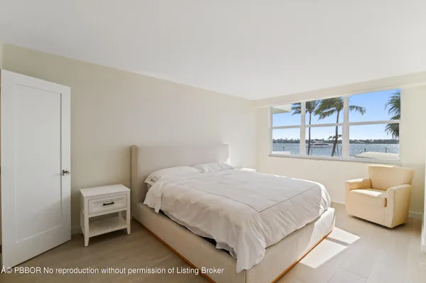 a bedroom with a white bed and a large window