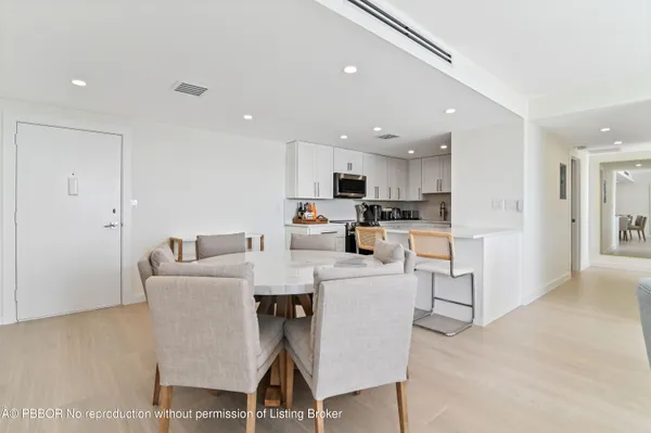 a living room with stainless steel appliances furniture a dining table and kitchen view