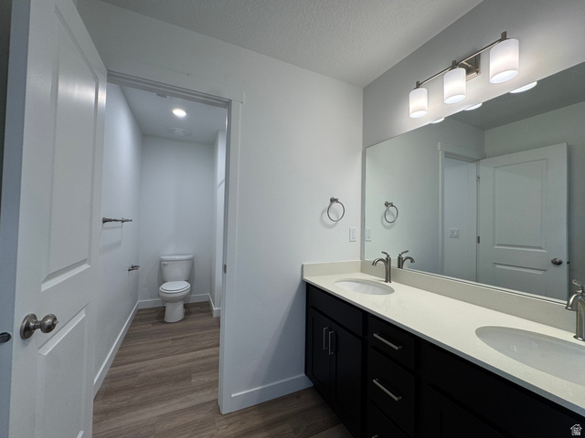 1883 West 1575th North, Unit 236 Layton, UT 84041 - Photo 18 of 22 Full bathroom with double vanity, dark wood-style floors, and a textured ceiling