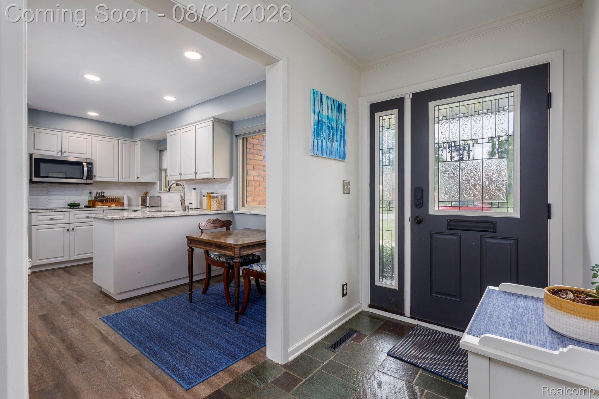 Entryway featuring a dark paneled door with decorative glass, slate-style tile flooring, and a sidelight