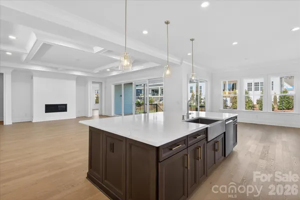 a kitchen with a stove a sink a center island and a wooden floor