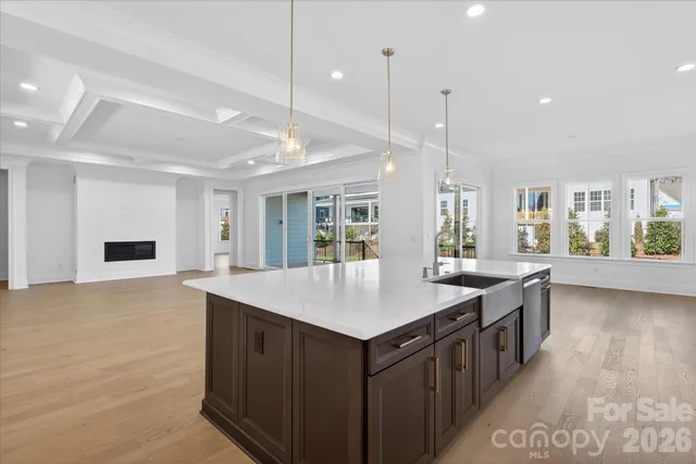 a kitchen with a stove a sink a center island and a wooden floor