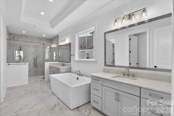 a bathroom with a sink double vanity granite tub shower and mirror