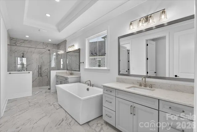 a bathroom with a sink double vanity granite tub shower and mirror