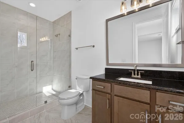 a bathroom with a granite countertop sink toilet a mirror and shower