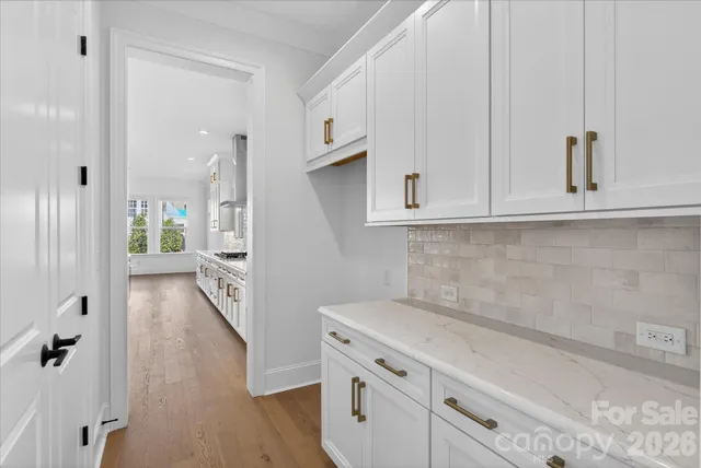 a view of a kitchen with white cabinets and wooden floor