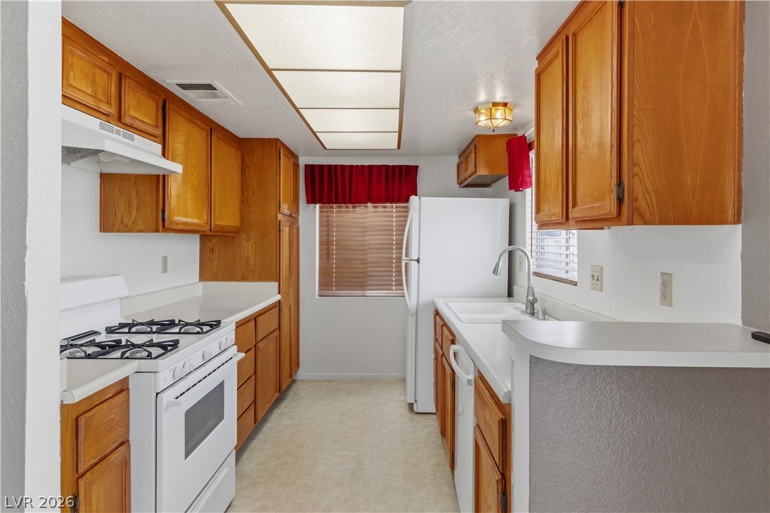 2124 Pebble Creek Lane Laughlin, NV 89029 - Photo 11 of 54 Kitchen featuring white appliances, light flooring, light countertops, and wood finish cabinets