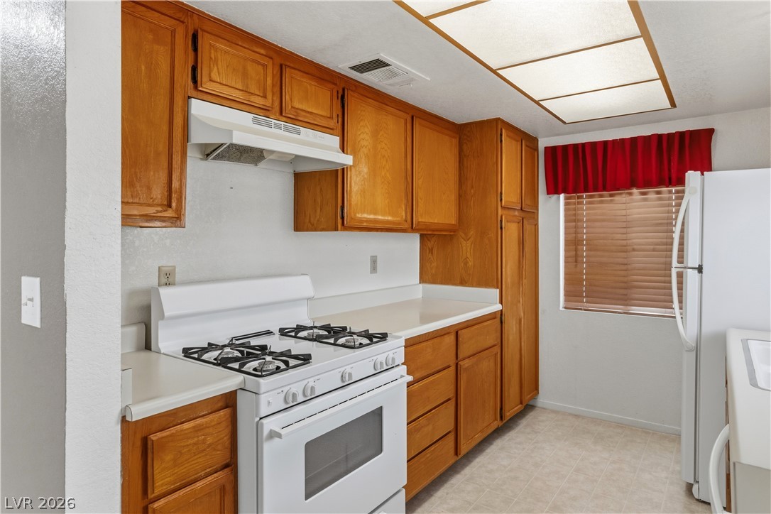 2124 Pebble Creek Lane Laughlin, NV 89029 - Photo 12 of 54 Kitchen featuring white appliances, wood finish cabinetry, light countertops, and light floors