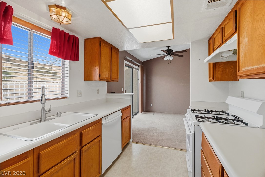 2124 Pebble Creek Lane Laughlin, NV 89029 - Photo 13 of 54 Kitchen featuring white appliances, light countertops, light flooring, wood finish cabinets, and ceiling fan