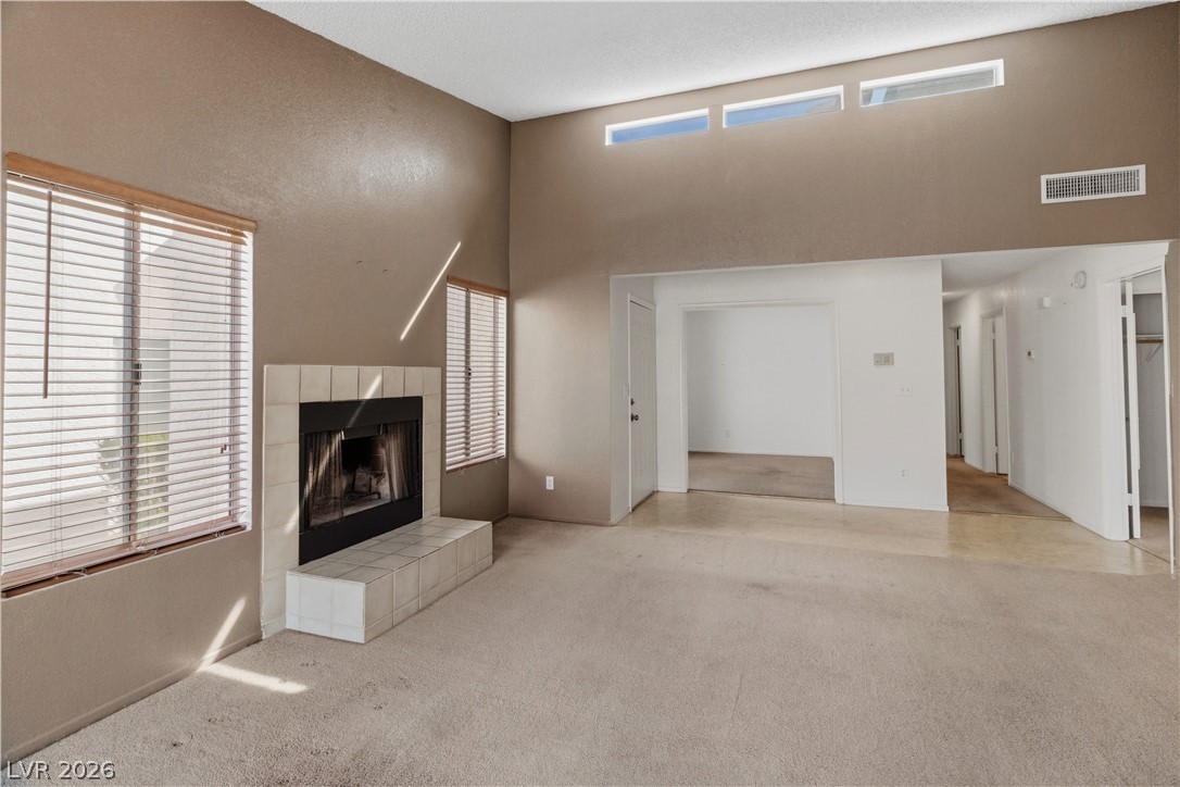 2124 Pebble Creek Lane Laughlin, NV 89029 - Photo 15 of 54 living room featuring a tile fireplace, light colored carpet, and a high ceiling