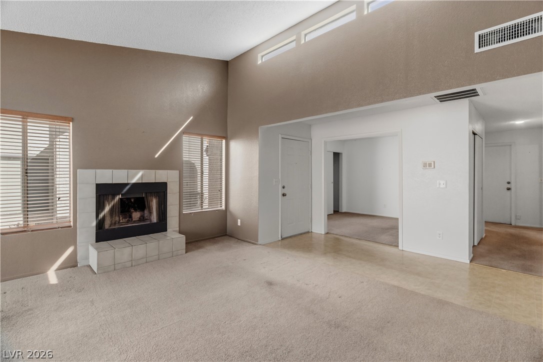 2124 Pebble Creek Lane Laughlin, NV 89029 - Photo 16 of 54 living room featuring carpet flooring, plenty of natural light, a fireplace, and a high ceiling
