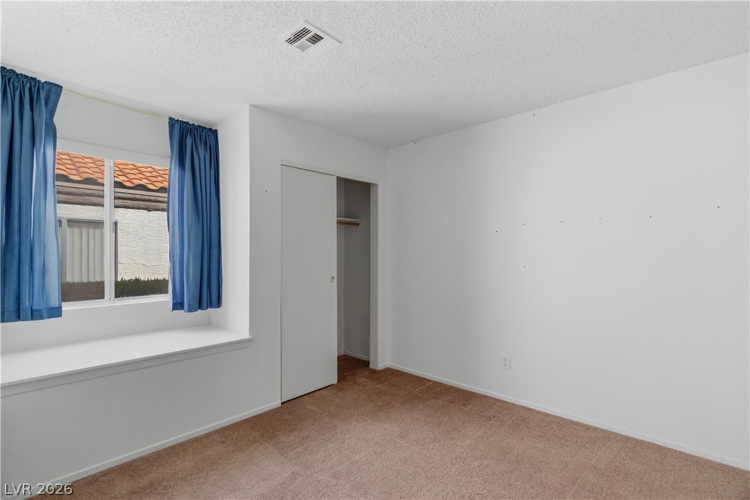 2124 Pebble Creek Lane Laughlin, NV 89029 - Photo 17 of 54 Secondary bedroom with light colored carpet, a textured ceiling, and a closet