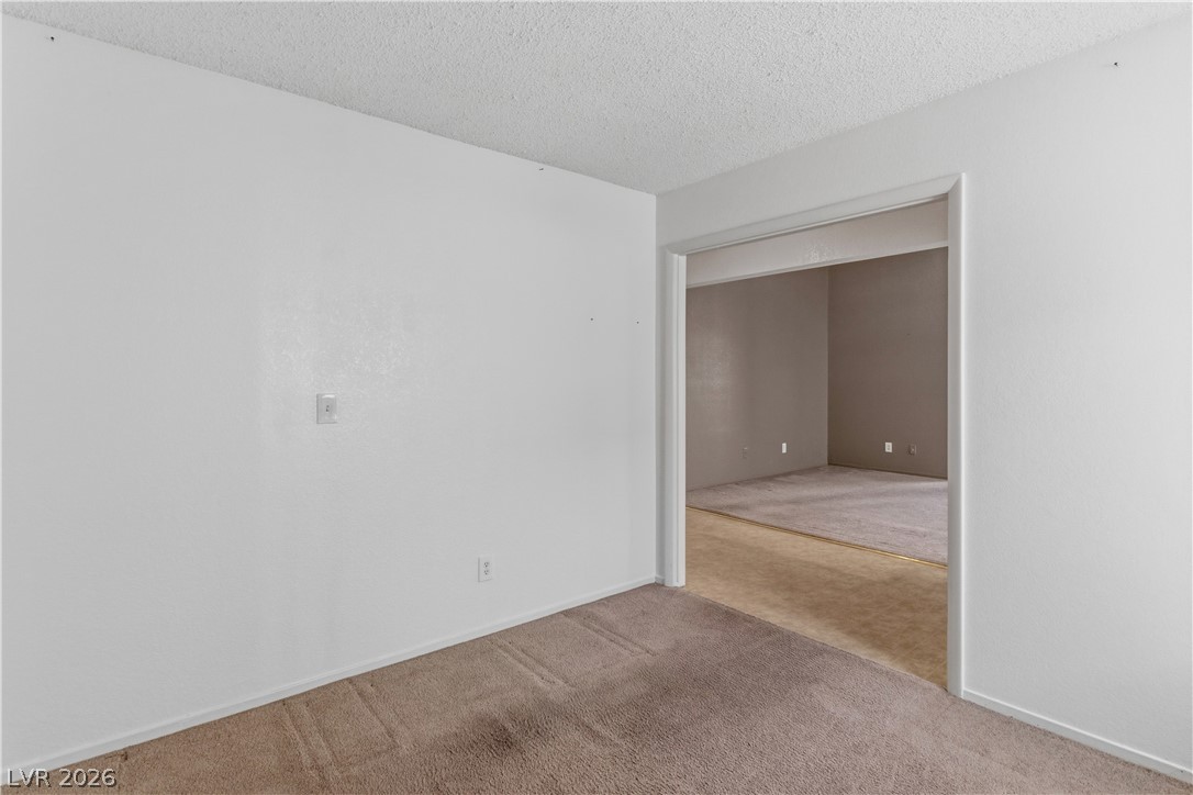 2124 Pebble Creek Lane Laughlin, NV 89029 - Photo 19 of 54 Second bedroom featuring light carpet and a textured ceiling