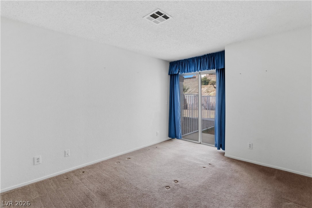 2124 Pebble Creek Lane Laughlin, NV 89029 - Photo 20 of 54 Primary bedroom featuring a textured ceiling and carpet floors