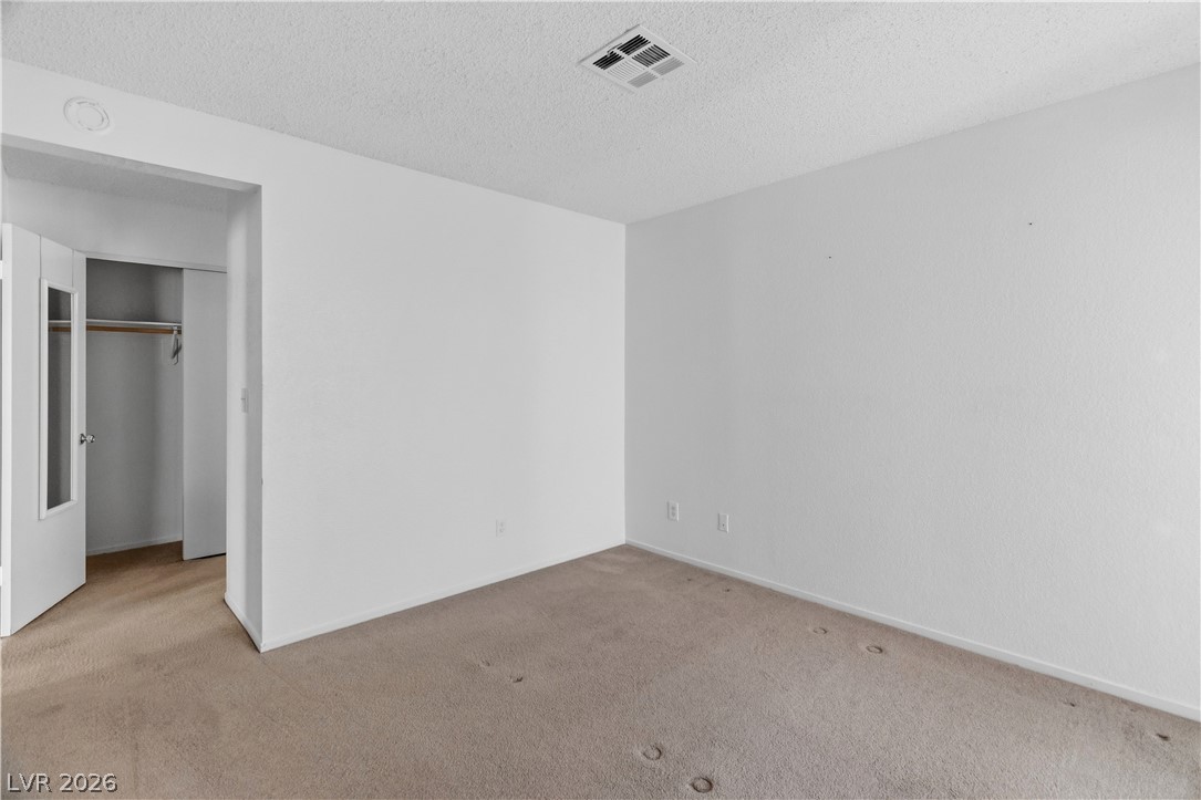 2124 Pebble Creek Lane Laughlin, NV 89029 - Photo 22 of 54 Primary bedroom featuring a closet, carpet, and a textured ceiling