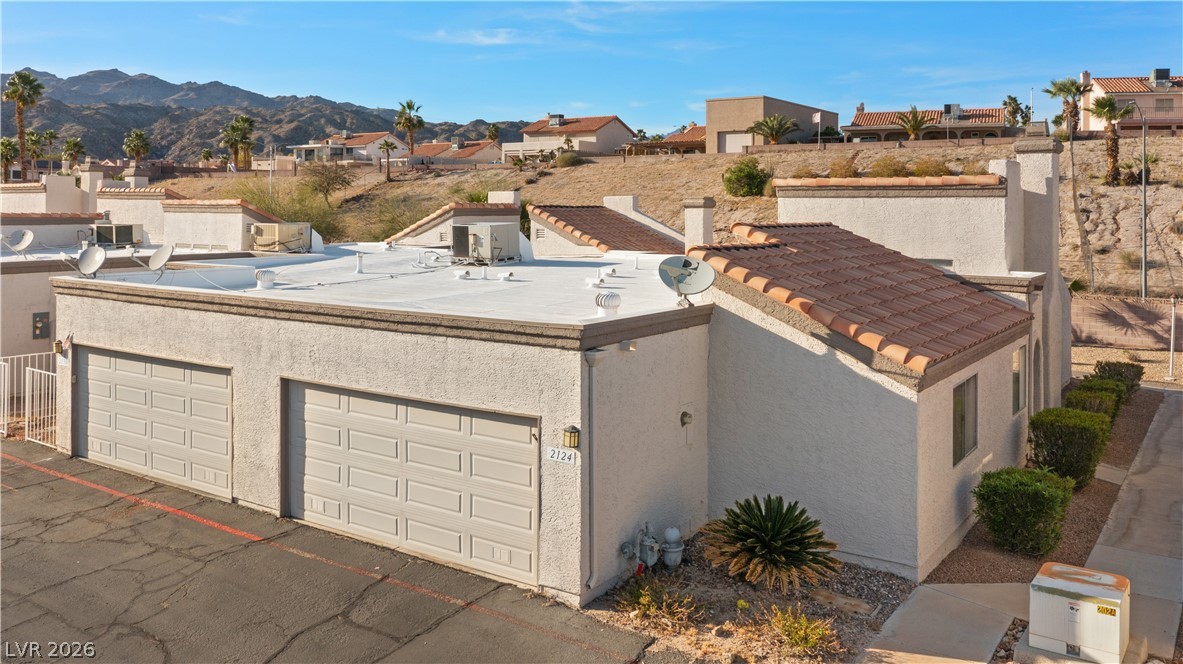 2124 Pebble Creek Lane Laughlin, NV 89029 - Photo 52 of 54 View of front of house with stucco siding, a residential view, a mountain view, and an attached garage