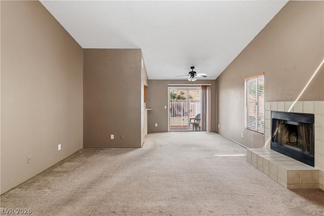 2124 Pebble Creek Lane Laughlin, NV 89029 - Photo 6 of 54 living room featuring vaulted ceiling, ceiling fan, carpet floors, and a fireplace
