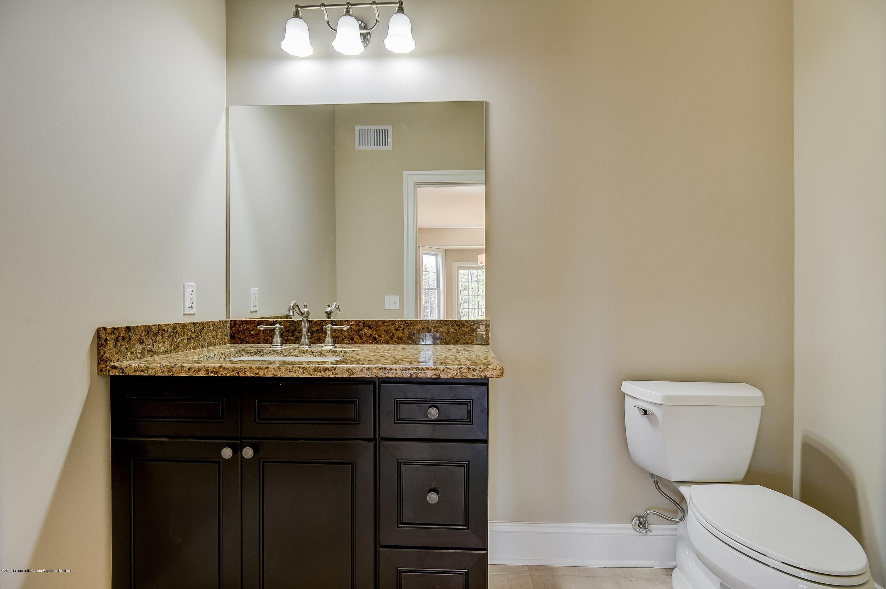 91 Obre Road Colts Neck, NJ 07722 - Photo 17 of 33 a bathroom with a granite countertop toilet a sink and a mirror