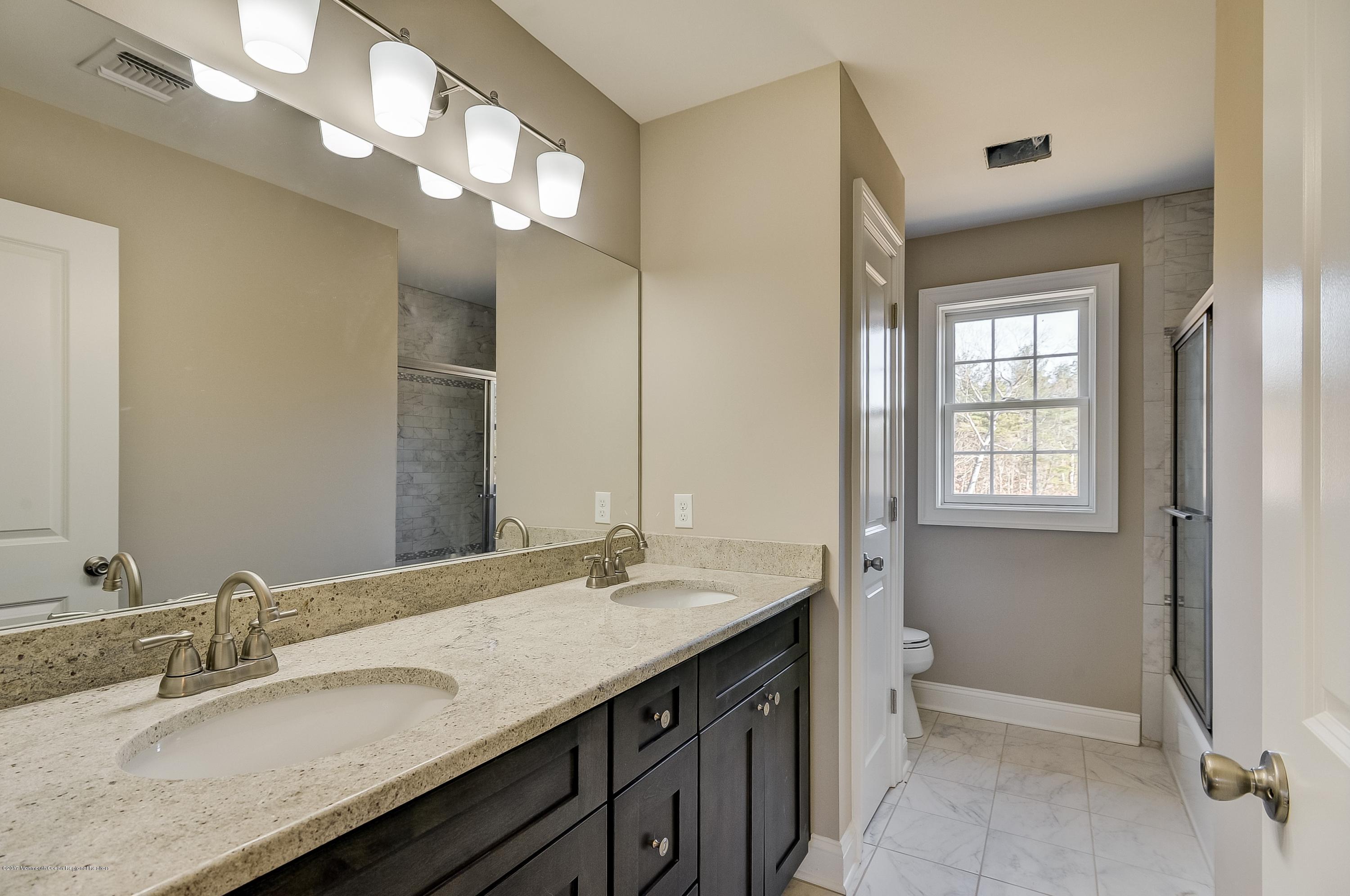 91 Obre Road Colts Neck, NJ 07722 - Photo 27 of 33 a bathroom with a granite countertop sink a light fixture and a mirror