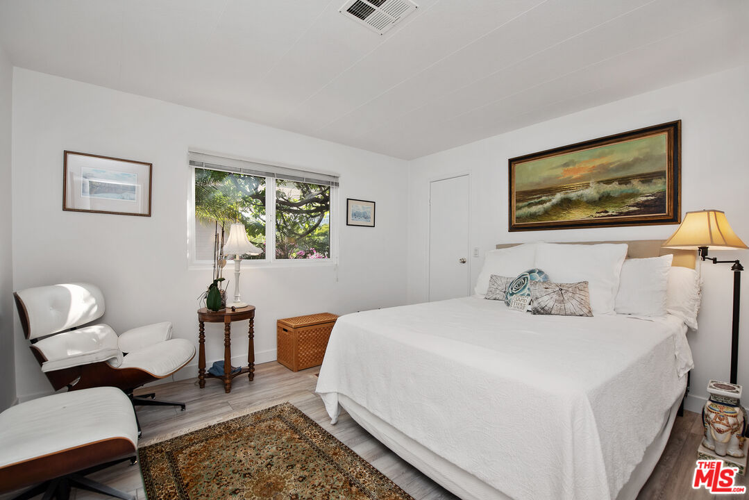 29500 Heathercliff Road, Unit 202 Malibu, CA 90265 - Photo 24 of 36 a bedroom with a bed and wooden floor