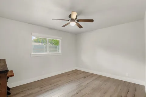 a view of empty room with wooden floor and fan