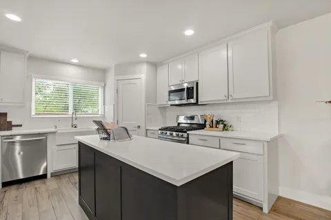 a kitchen with a sink stove a sink a refrigerator and cabinets