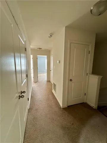 a view of a hallway with wooden floor and a bathroom