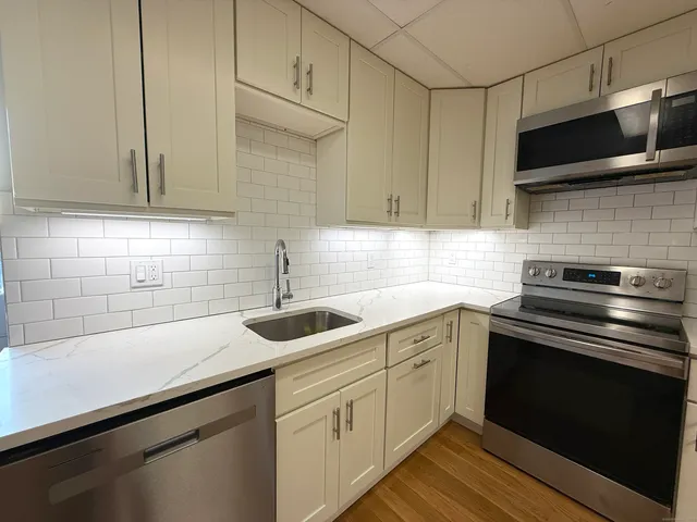 a kitchen with stainless steel appliances granite countertop a sink a stove and microwave