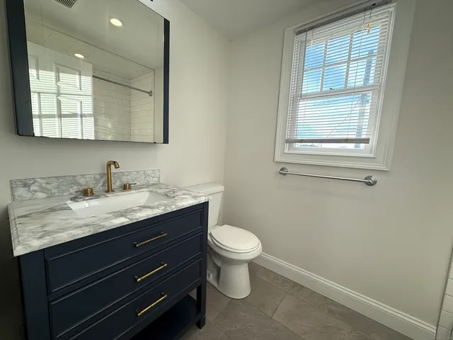 a bathroom with a granite countertop toilet sink and mirror
