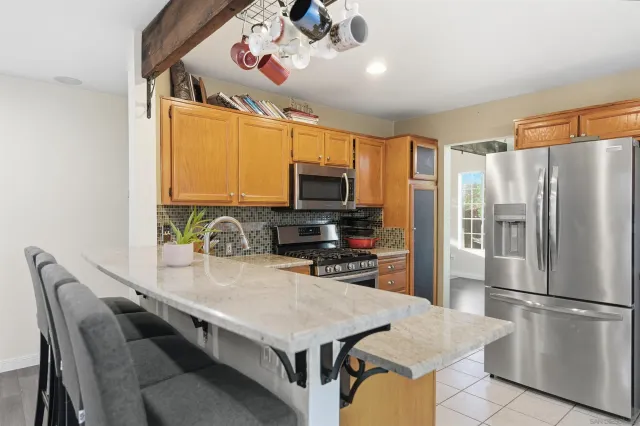 a kitchen with stainless steel appliances granite countertop a refrigerator a sink dishwasher a stove a dining table and chairs with wooden floor