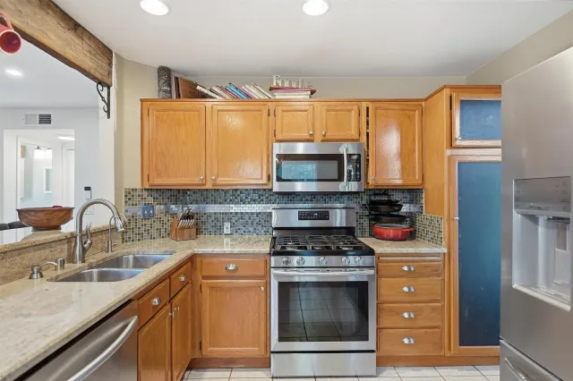 a kitchen with stainless steel appliances granite countertop a stove a sink and a microwave
