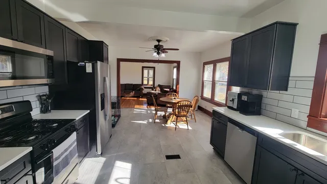 a kitchen with stainless steel appliances granite countertop a refrigerator a stove top oven a sink dishwasher and dining table with wooden floor