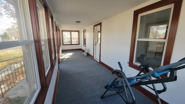 a view of a hallway with wooden floor and windows with an outdoor view
