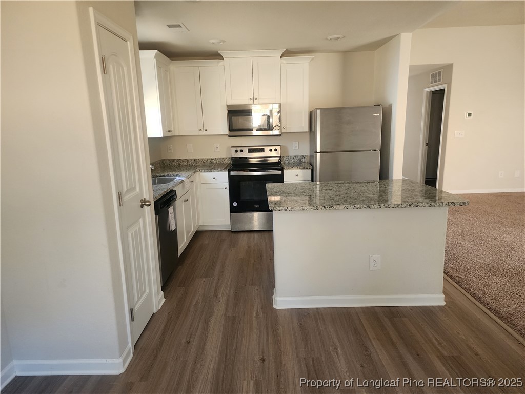 207 Barnsley Road Angier, NC 27501 - Photo 7 of 16 a kitchen with a refrigerator a stove top oven and wooden floor