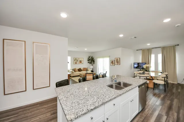 a view of kitchen island a sink wooden floor and living room view