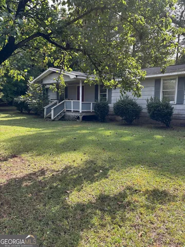 a view of a house with a yard and a large tree