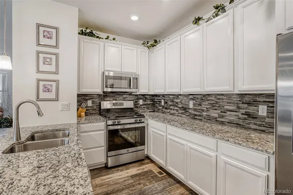 a kitchen with stainless steel appliances granite countertop a sink stove and cabinets