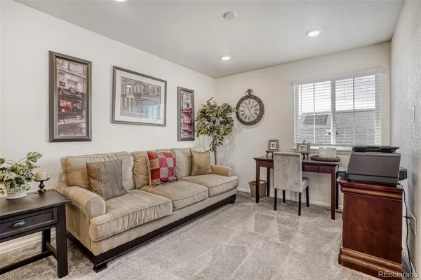 a living room with furniture a clock on wall and a window