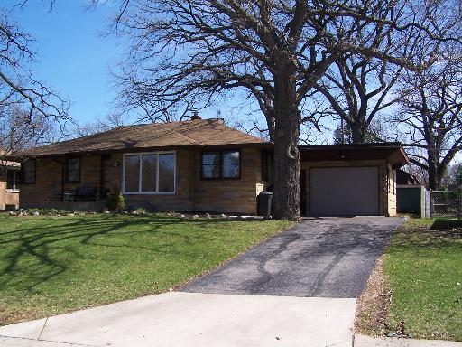 a front view of a house with a garden and trees