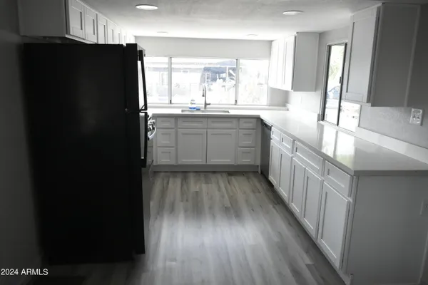 a view of a refrigerator in kitchen and an empty room