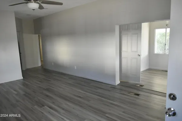 a view of an empty room with a window and wooden floor