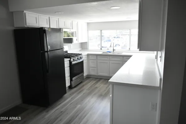 a kitchen with granite countertop a refrigerator a sink and dishwasher with wooden floor