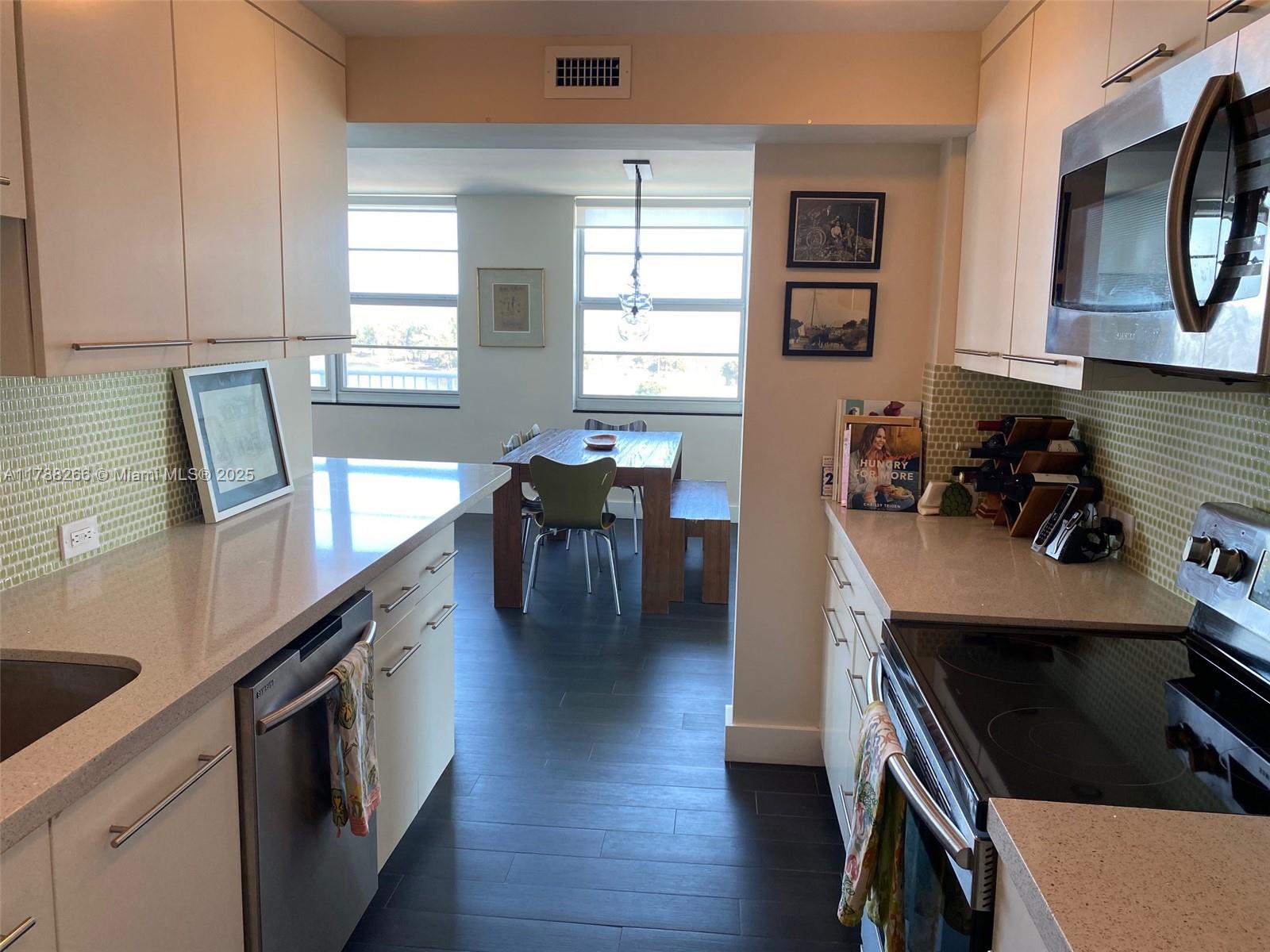 150 Southeast 25th Road, Unit 7A Miami, FL 33129 - Photo 8 of 18 a kitchen with stainless steel appliances kitchen island granite countertop a stove a sink a refrigerator dining table and chairs