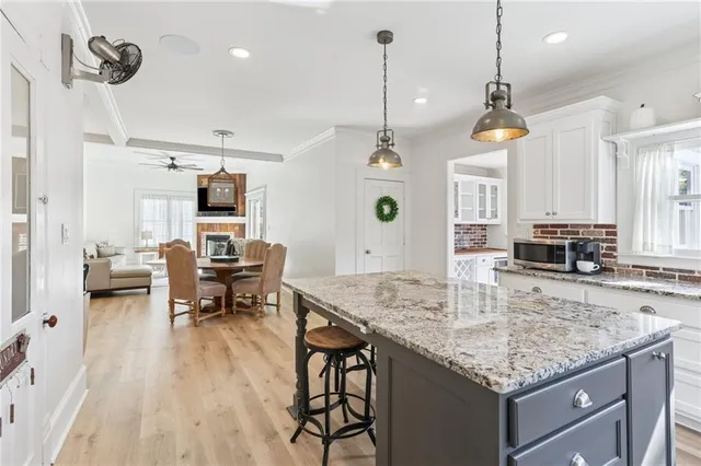 a kitchen with kitchen island granite countertop a stove a sink a dining table and chairs with wooden floor