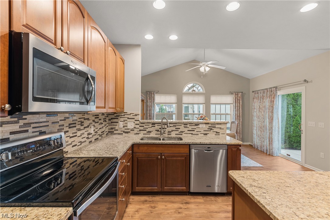 279 Sandstone Ridge Way Berea, OH 44017 - Photo 11 of 29 Kitchen with backsplash, vaulted ceiling, light hardwood floors, stainless steel appliances, and light stone counters