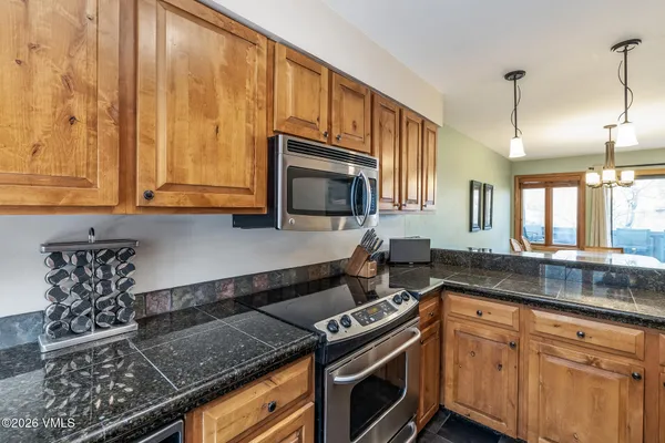 a kitchen with stainless steel appliances granite countertop a stove a sink and a microwave